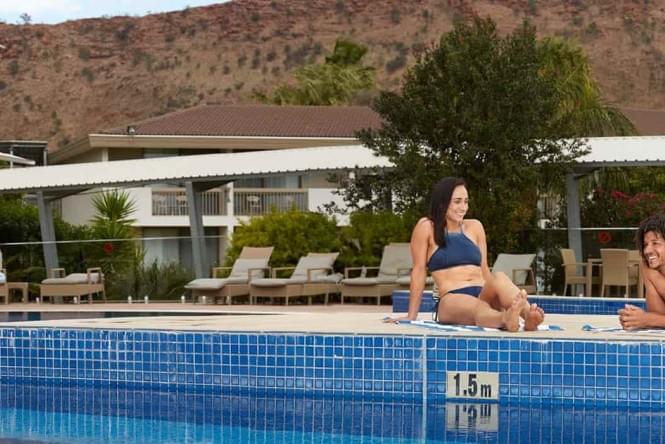 A couple sunbaking next to pool at Alice Springs accommodation